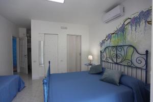 a bedroom with a blue bed with a painting on the wall at Jungle Rooms in Cetara