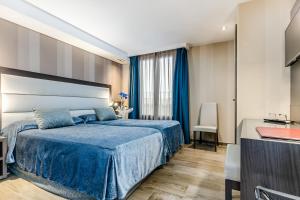 Un dormitorio con una cama azul y una ventana en Hotel Reina Cristina, en Teruel