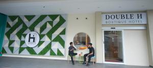 Double H Boutique Hotel في كوالا ترغكانو: يجلس رجلان على طاولة خارج المبنى