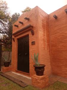 een klein huis met een zwarte deur en een potplant bij Casa Darragueira in Chacras de Coria