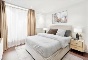 biała sypialnia z dużym łóżkiem i oknem w obiekcie Beautiful Apartment by Piccadilly Circus w mieście Edmonton