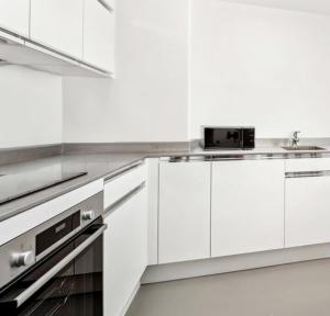 Biała kuchnia z białymi szafkami i zlewem w obiekcie Beautiful Apartment by Piccadilly Circus w mieście Edmonton