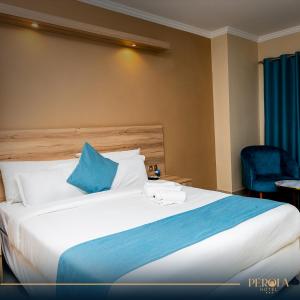 een hotelkamer met een groot bed met blauwe kussens bij PEROLA HOTEl in Maputo