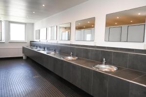 eine Reihe von Waschbecken in einer öffentlichen Toilette mit Spiegeln in der Unterkunft Sleep Space 21 - Green Tiny Village Harlesiel in Wittmund