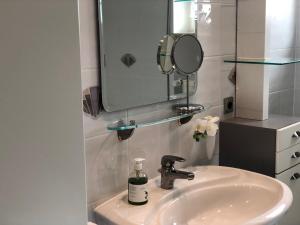 een wastafel in de badkamer met een spiegel en een fles zeep bij Weingut Bastian in Brauneberg