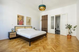 een slaapkamer met een bed en een houten vloer bij Imperial City Apartment in Wenen