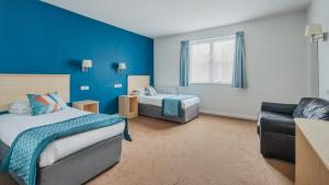 a blue room with two beds and a couch at Wookey Hole Hotel in Wells