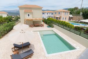 a swimming pool with two umbrellas and two chairs at Vasilopoulos Residences - Villa Chloe with private pool in Argostoli