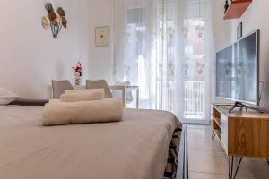 a white bedroom with a large bed and a television at [20 minuti dal Duomo] Milano Smart Apartment in Sesto San Giovanni