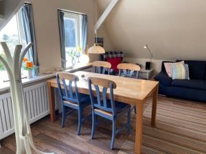 a dining room with a wooden table and chairs at Deichhof Whg 27 in Dunsum