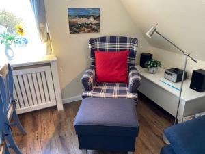a chair with a red pillow in a room at Deichhof Whg 27 in Dunsum