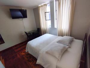 una camera con un letto bianco e una finestra di hospedaje encantada a Cajamarca