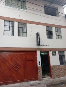 - un bâtiment blanc avec une porte de garage en bois dans l'établissement hospedaje encantada, à Cajamarca