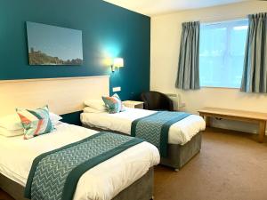 Wookey Hole Hotel في ويلْزْ: غرفة فندقية بسريرين ومكتب