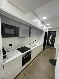 a white kitchen with a sink and a microwave at HOME 12 in Librazhd