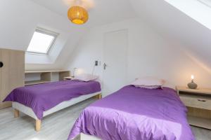 トレガンにあるPenty house 500m de la plageの白い部屋のベッド2台 紫色のシーツ付