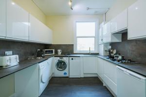 eine weiße Küche mit Waschmaschine in der Unterkunft 4 bedroom Stunning Flat Near Westfield & Trains in London