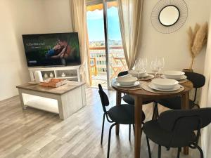 Un comedor con una mesa con sillas y un televisor. en Joli 2 pièces - Proche aéroport - Terrasse vue mer, en Niza