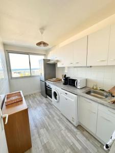una cocina con gabinetes blancos y una lavadora y secadora en Joli 2 pièces - Proche aéroport - Terrasse vue mer, en Niza 10 fotos más