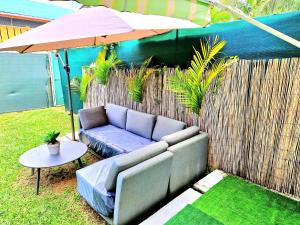 a couch sitting next to a fence with an umbrella at T2 Paisible et spacieux in Baie-Mahault