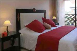 a bedroom with a large bed with red pillows at Appart-Oasis Piscine et Terrasses in Marrakesh
