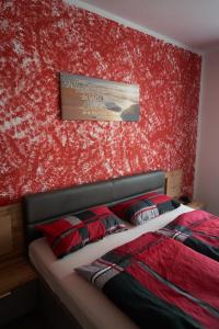 Un dormitorio con una pared de acento rojo y una cama en Bei Charlotte, en Sonneberg