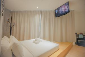 a bedroom with a white bed with a flat screen tv at Double H Boutique Hotel in Kuala Terengganu