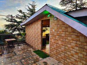 a small brick house with a balcony with a bench at Jakhu Vibes in Shimla