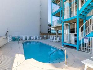 una piscina con sillas blancas y un edificio en The Beach is Only Steps Away (F2) BEACHFRONT - Sleeps 8 en Gulf Shores
