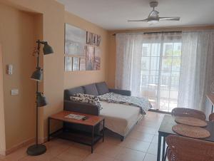 a bedroom with a bed and a couch and a window at Greatly located apartment with heated pool, Los Cristianos in Los Cristianos
