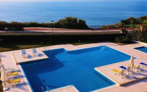 ein großer Pool mit Stühlen und das Meer in der Unterkunft Sea View W Pool, Terrace & Parking in Cascais