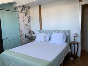un letto con lenzuola e cuscini bianchi in una camera da letto di La Croix Blanche a Dax