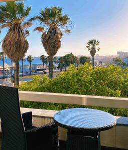 un patio con mesa, sillas y palmeras en Sea View W Balcony 2 Mins Walk To Beach & Casino, en Estoril