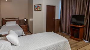 コチャバンバにあるEl Prado Hotelのベッド2台とテレビが備わるホテルルームです。