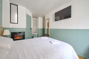 1 dormitorio con cama blanca y chimenea en LE PADIRAC, en París