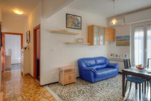 a living room with a blue chair and a table at A Gonfie Vele VADOALMARE Immobiliare in Vado Ligure
