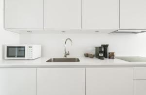 a white kitchen with a sink and a microwave at Modern 2-bed apartment in Ørestaden in Copenhagen