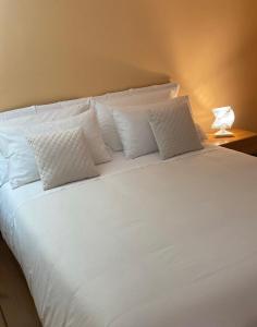 ein großes weißes Bett mit weißen Kissen darauf in der Unterkunft CASA VACANZA TINDARA in Civitavecchia