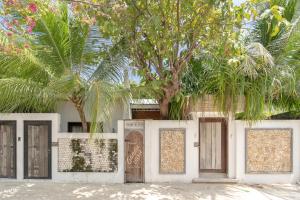 a white fence with doors and palm trees at Brickwood Ganduvaru Private Villas in Rasdu