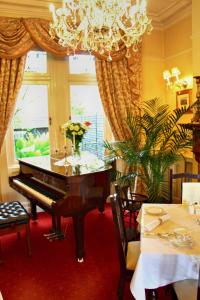 a grand piano in a dining room with a chandelier at Innisfree House in Dundalk