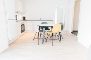 オーデンセにあるCool 1-bed w. private terraceの白いキャビネット、テーブルと椅子付きのキッチンが備わります。