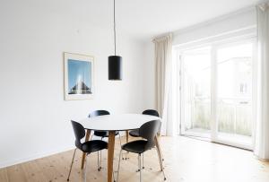 Refurbished 1-BR apartment in Charlottenlund - 208 في شارلوت لوند: غرفة طعام بيضاء مع طاولة وكراسي بيضاء +صورتان