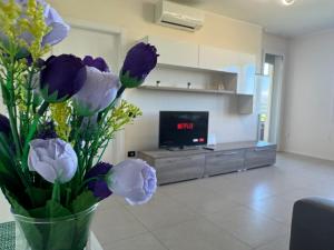 a vase with purple and yellow flowers in a living room at Via Battisti 7_Pero in Pero