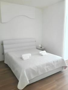 een witte slaapkamer met een bed met twee handdoeken erop bij 2 bedrooms apartement at Polignano a Mare 50 m away from the beach with furnished terrace and wifi in Polignano a Mare