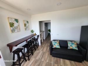 ein Wohnzimmer mit einem schwarzen Sofa und einer Bar in der Unterkunft Sea Breeze inn 101 in Providencia
