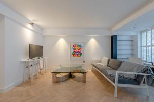 a living room with a couch and a tv at Sleek & Stylish 2BD Flat - Warren Street in London