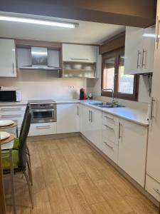 a kitchen with white cabinets and a table and a sink at Brisa mariña in Isla de Arosa +10 photos
