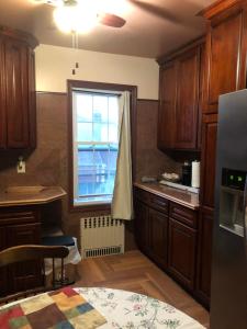 una cocina con armarios de madera y una ventana en Room to stay in, en South Ozone Park