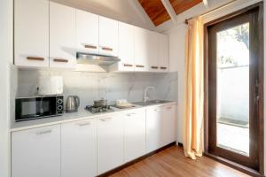 a kitchen with white cabinets and a microwave and a window at Brickwood Ganduvaru Private Villas in Rasdu
