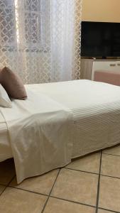ein Bett mit einer weißen Bettdecke und einem TV in der Unterkunft CASA VACANZA TINDARA in Civitavecchia
